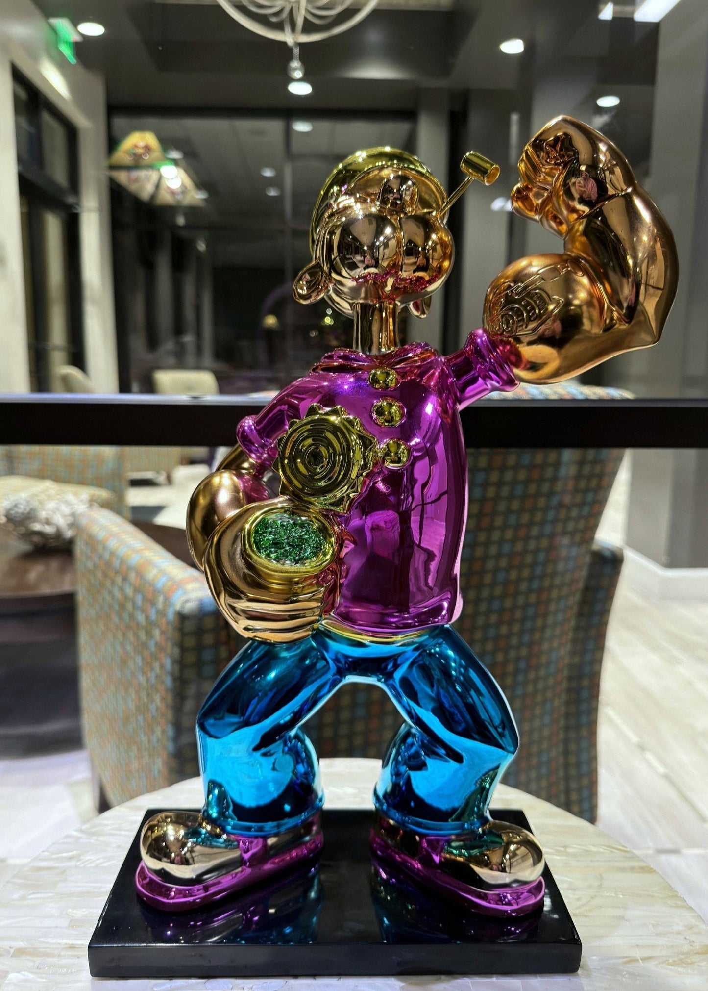 Colorful sculpture of a muscular figure with gold arms and blue legs on a black base.