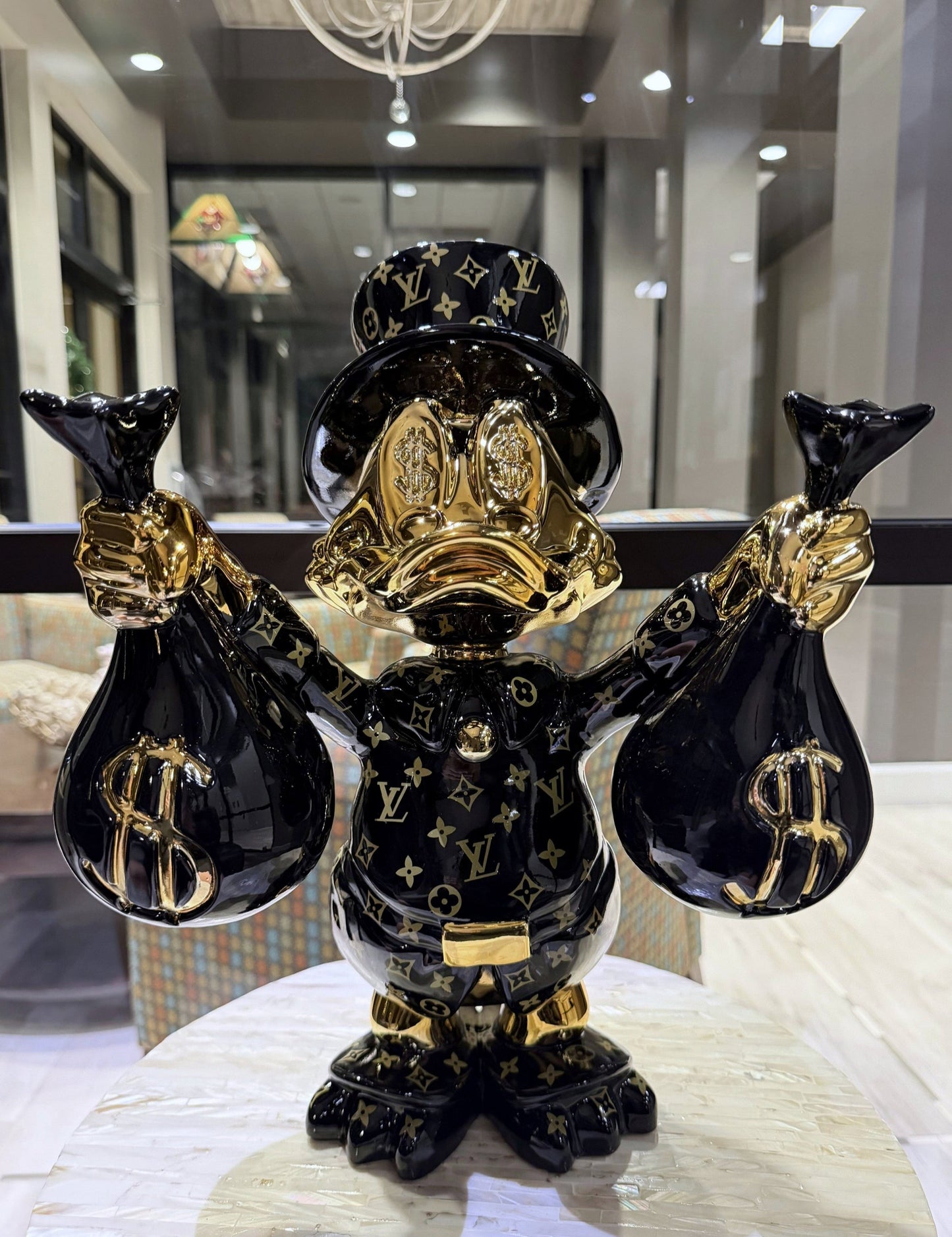 Decorative figurine resembling a richly dressed duck with gold accents and black bags on a table.