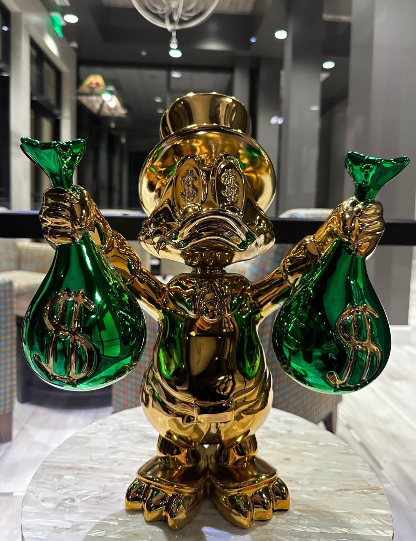 Gold and green decorative figure with dollar signs on a marble surface
