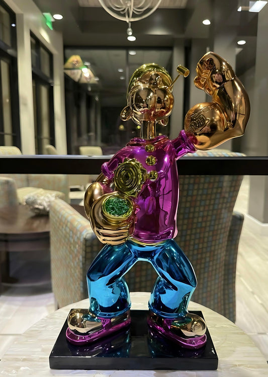 Colorful sculpture of a muscular figure with gold arms and blue legs on a black base.