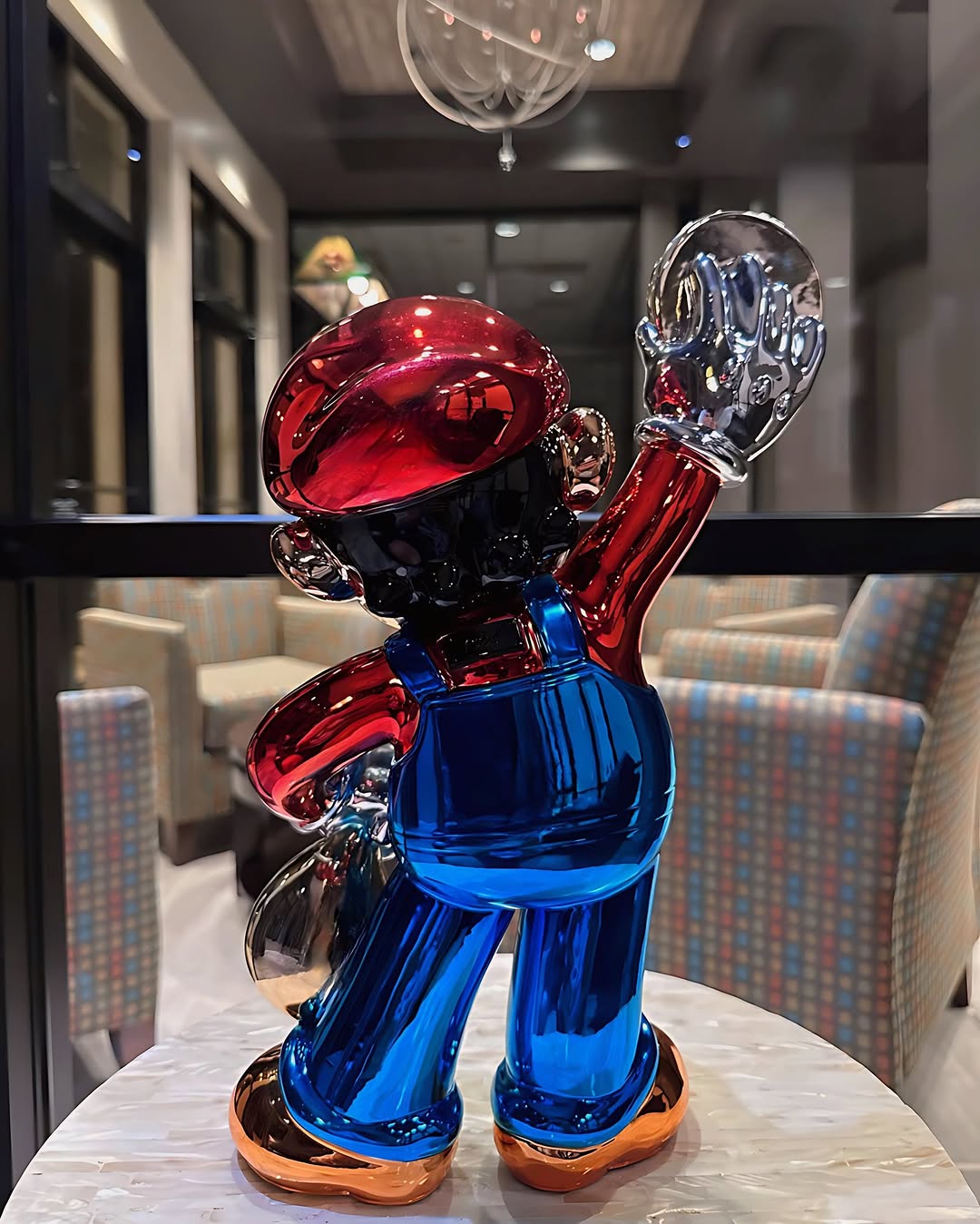 Back angle of Super Mario money bag chrome sculpture featuring vibrant red and blue metallic detailing.